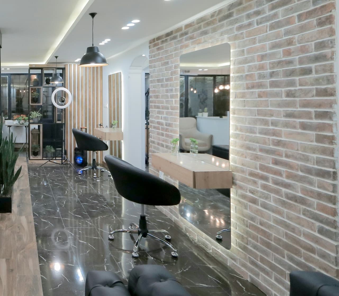 Mermer zeminli, tuğla duvarlı ve aydınlatmalı aynalı modern bir güzellik salonu